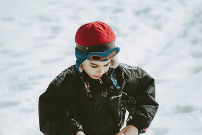 Boy in warm clothing walking on snow covered field