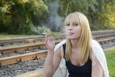 Portrait of woman smoking cigarette while sitting outdoors