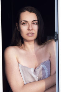 Portrait of beautiful woman standing by window at home