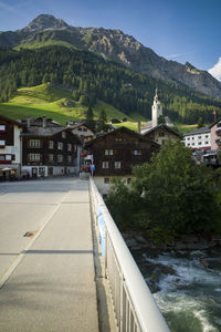 Road amidst buildings and mountains against sky