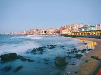 Scenic view of sea and buildings against clear sky