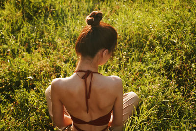Rear view of young woman sitting on grass