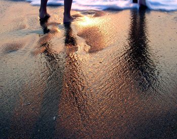 Reflection of man in puddle on beach