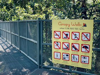 Text on fence against trees