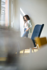 Businesswoman talking on smart phone in front of wall