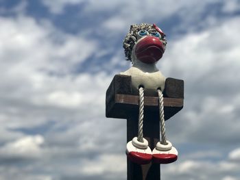 Funny figure sitting on  a high seat in front  of blue sky