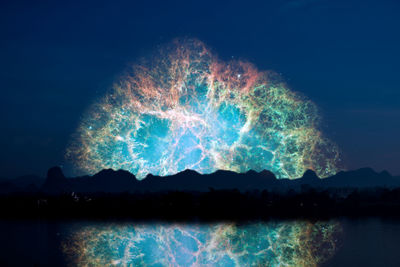 Firework display over lake against sky at night