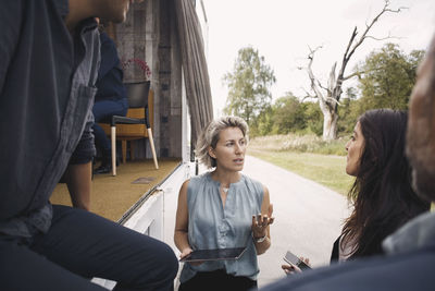 Businesswoman holding digital tablet while discussing with colleagues by portable office truck