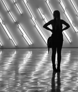 Woman standing in front of wall with illuminated fluorescent lights