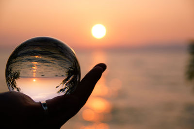 Close-up of hand holding sun during sunset