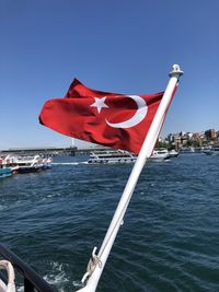 Red flag on boat against clear blue sky