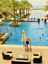 Chairs by swimming pool against sea