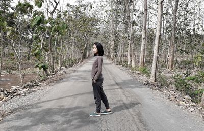 Full length of woman standing on road amidst trees