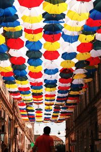 Rear view of man standing under umbrella hanging amidst buildings