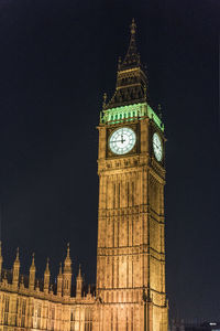 Low angle view of clock tower at night