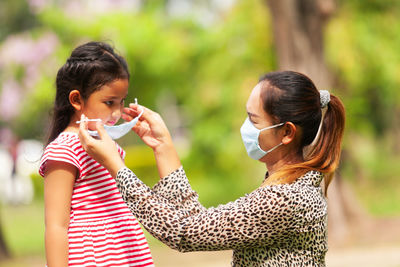 Mother wearing mask to daughter outdoors