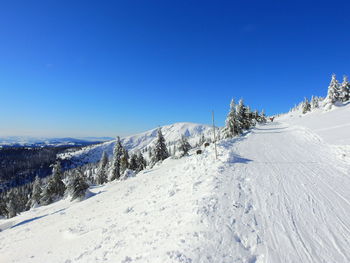 Snow covered landscape against clear blue sky