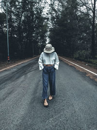 Full length of woman standing on road against trees