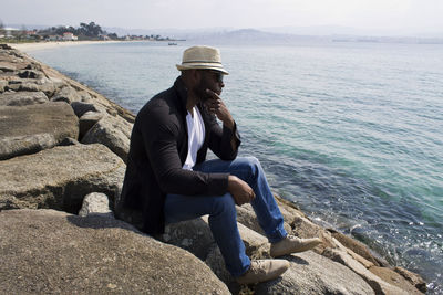 Man sitting on rock looking at sea