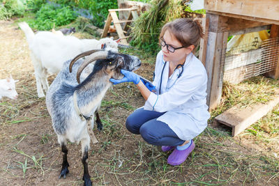 Side view of woman with goat on field