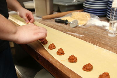 Midsection of person preparing cookies in kitchen