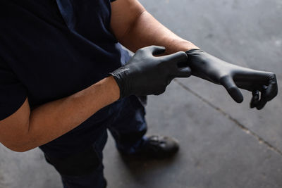 From above anonymous male employee putting on latex gloves during work in garage