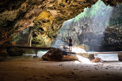 Rear view of woman standing in cave