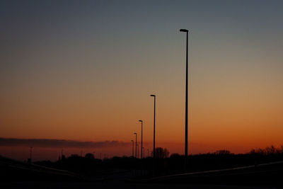 Silhouette street against sky during sunset