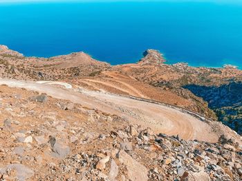 Scenic view of a winding road in an arid landscape against blue water