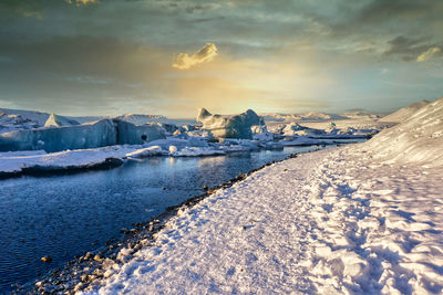 Scenic view of frozen lake against sky during sunset