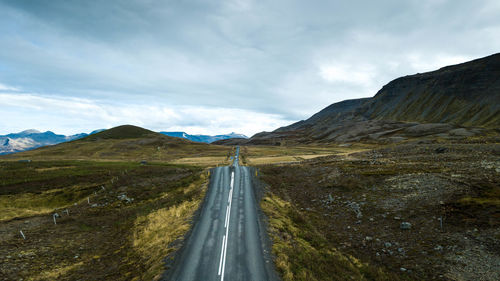 Road leading towards mountains against sky