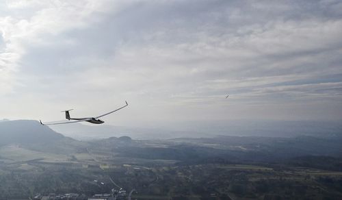 Airplane over landscape against sky