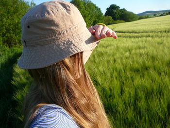 Close-up of woman wearing hat and shielding eyes while standing on land