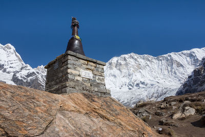 Low angle view of snowcapped mountains against clear blue sky