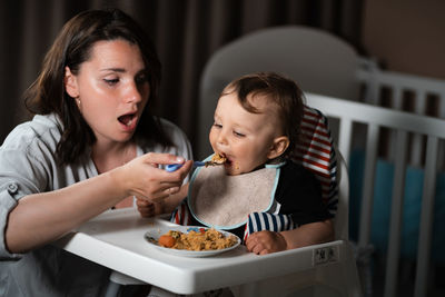 Mother and daughter sitting on table