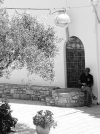 Rear view of woman sitting against building