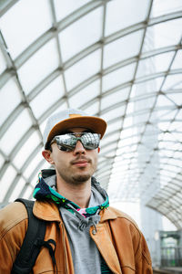 Portrait of young man wearing cap against ceiling