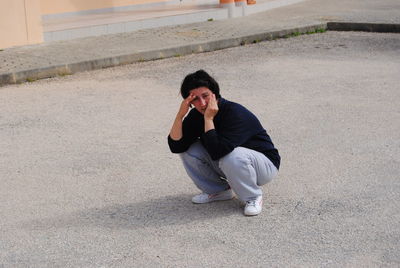 Portrait of woman crouching on walkway