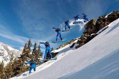 Low angle view of people on snowcapped mountain against blue sky