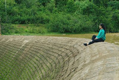 Side view of woman sitting on grassland