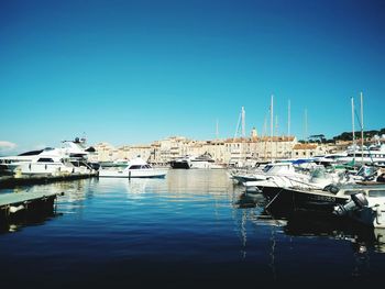 Sailboats moored on sea against clear blue sky