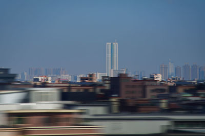 Blurred motion of buildings in city against clear sky