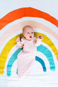 View from above of a newborn baby lying on a rainbow painted blanket