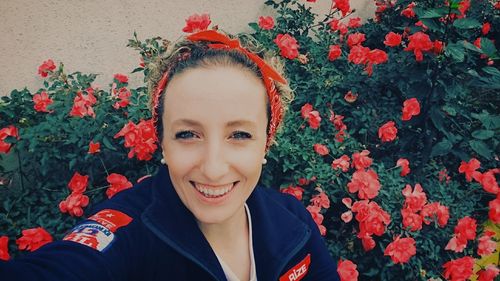 Portrait of smiling young woman standing against plants