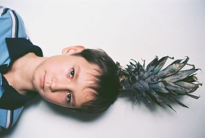 High angle portrait of boy with leaves on white background