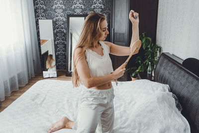 Young woman using hairbrush at home