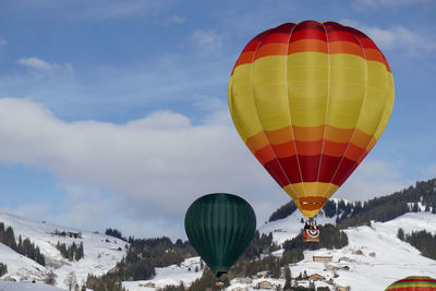 Hot air balloons flying over snowcapped mountains against sky