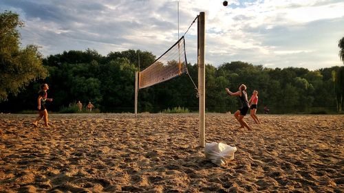 Children playing on sand against sky