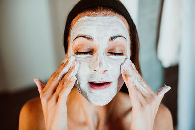 Close-up of woman applying facial mask