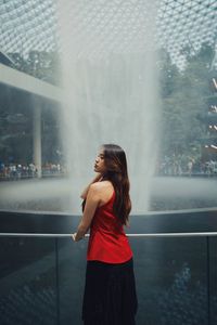 Rear view of woman standing by fountain outdoors